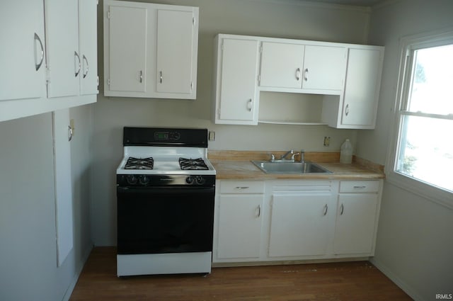 kitchen featuring white cabinets, dark wood-style flooring, light countertops, black gas stove, and a sink