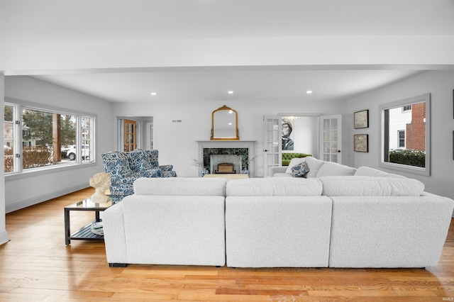 living area featuring a high end fireplace, light wood-type flooring, visible vents, and recessed lighting