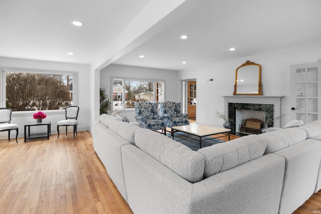 living room featuring a high end fireplace, baseboards, recessed lighting, and wood finished floors