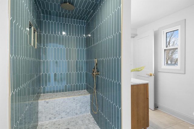 bathroom featuring tile patterned floors, a tile shower, vanity, and baseboards