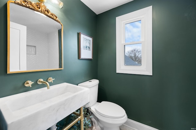 bathroom with a sink, toilet, and baseboards