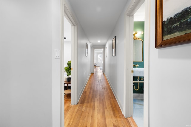 hall featuring light wood-type flooring, baseboards, and recessed lighting