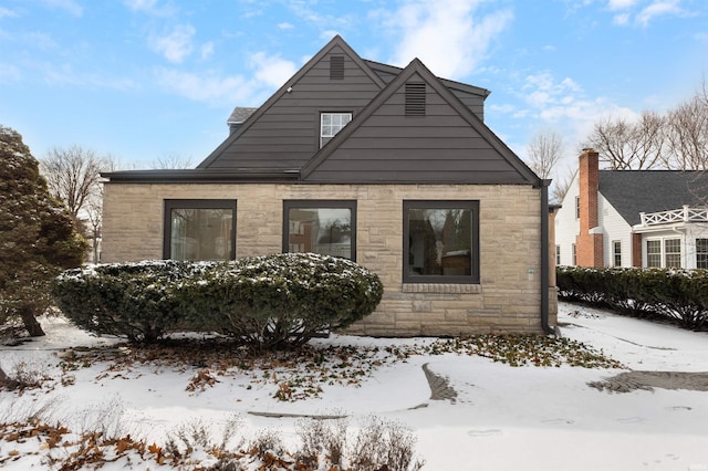 view of snow covered exterior featuring stone siding