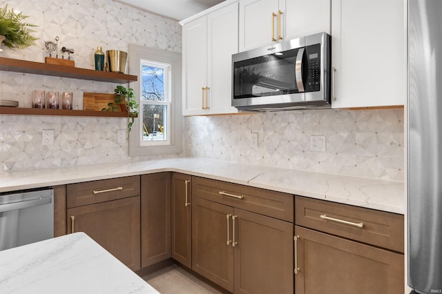 kitchen featuring light stone counters, stainless steel appliances, white cabinetry, open shelves, and backsplash