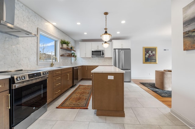 kitchen with appliances with stainless steel finishes, light countertops, wall chimney range hood, white cabinetry, and open shelves