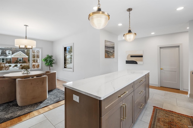 kitchen with open floor plan, light stone counters, recessed lighting, and pendant lighting