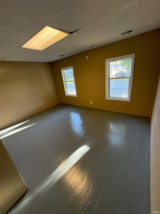 spare room featuring a paneled ceiling, visible vents, and wood finished floors