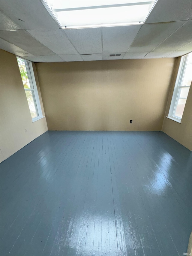 below grade area with visible vents, a drop ceiling, and wood finished floors