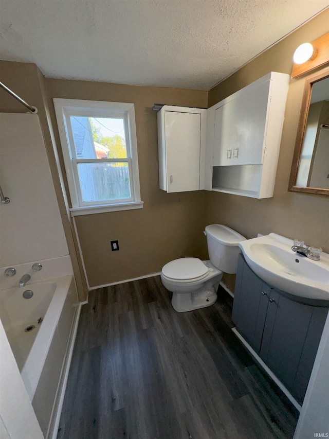 full bath featuring a textured ceiling, toilet, wood finished floors, vanity, and baseboards