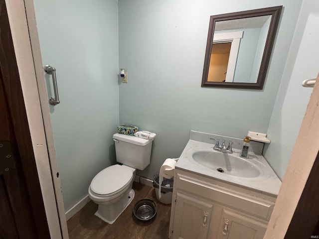 bathroom with toilet, baseboards, wood finished floors, and vanity