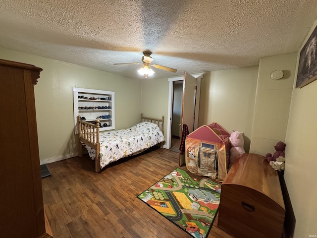 bedroom featuring dark wood-style floors, a textured ceiling, baseboards, and a ceiling fan