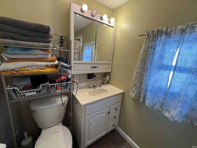 bathroom with baseboards, vanity, and toilet