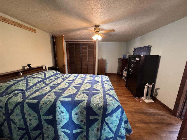 bedroom featuring a closet, dark wood-type flooring, a ceiling fan, a textured ceiling, and baseboards