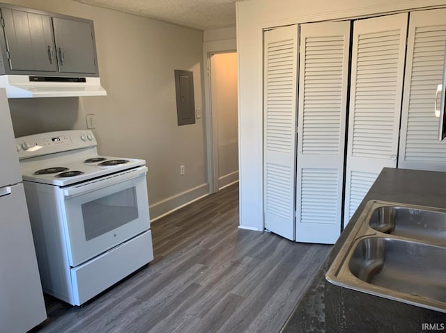 kitchen with a textured ceiling, under cabinet range hood, white appliances, a sink, and electric panel