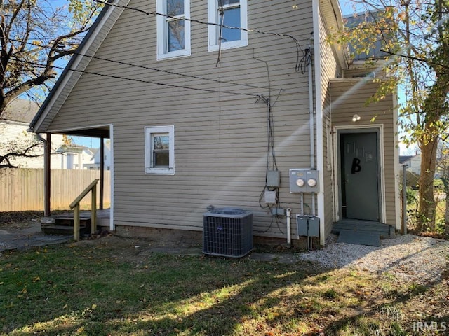 back of house with entry steps, central AC unit, a lawn, and fence