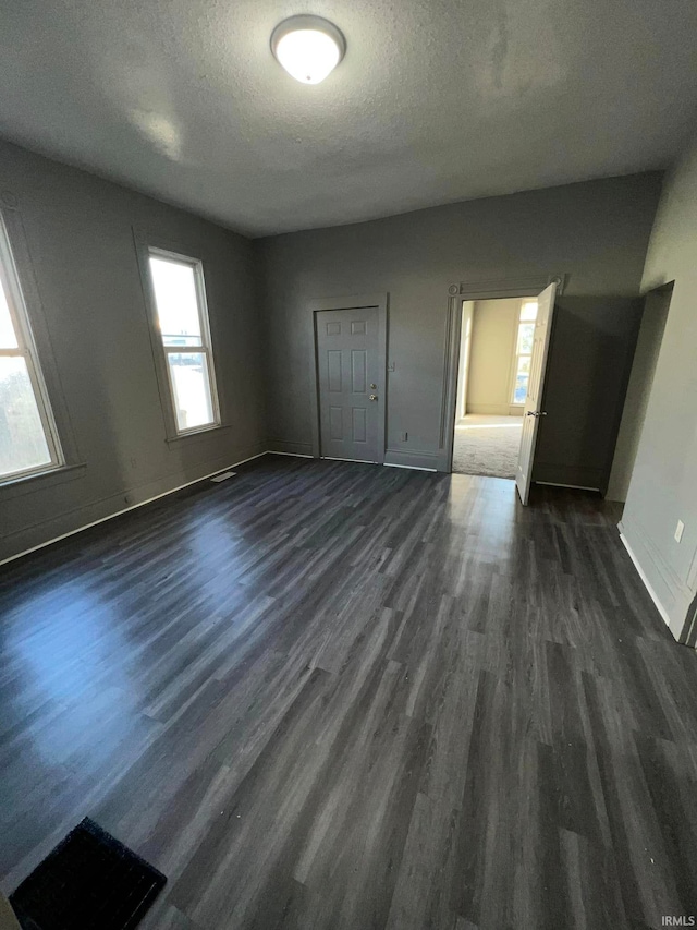 unfurnished room featuring dark wood-style floors, a textured ceiling, and baseboards