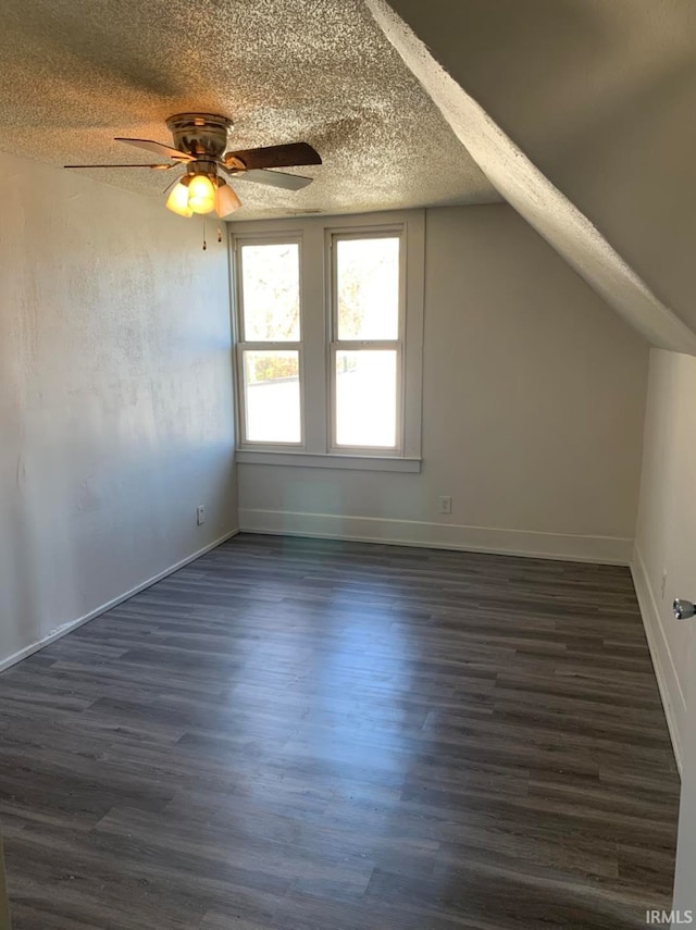 additional living space with lofted ceiling, baseboards, dark wood finished floors, and a textured ceiling