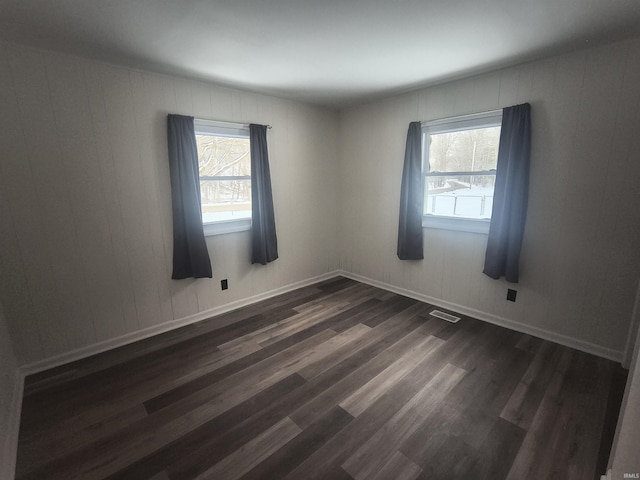 spare room featuring visible vents, dark wood finished floors, and baseboards