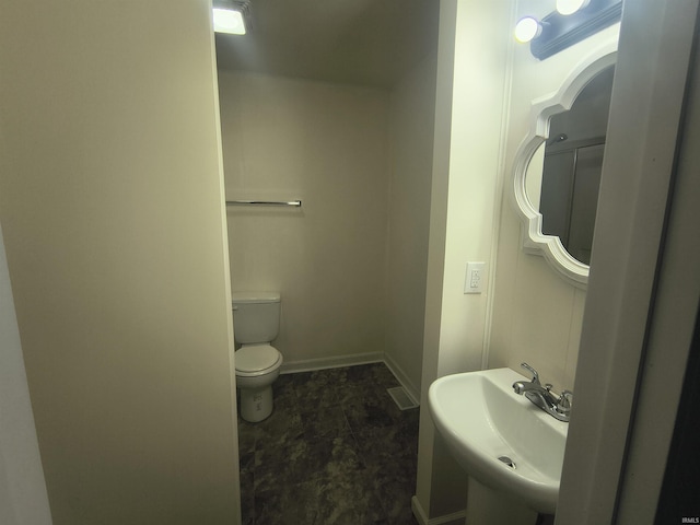 bathroom with toilet, baseboards, and a sink