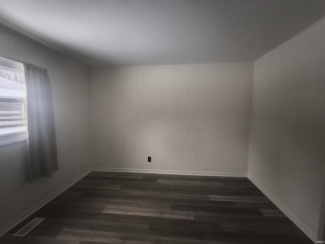 spare room with dark wood-style floors, baseboards, and visible vents