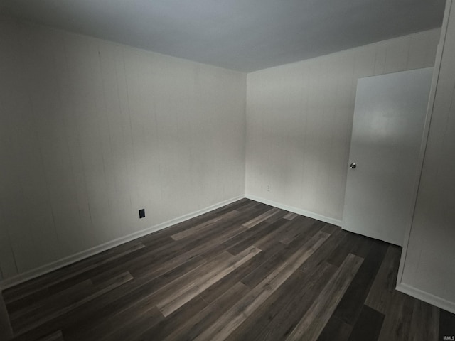 unfurnished room with baseboards and dark wood finished floors