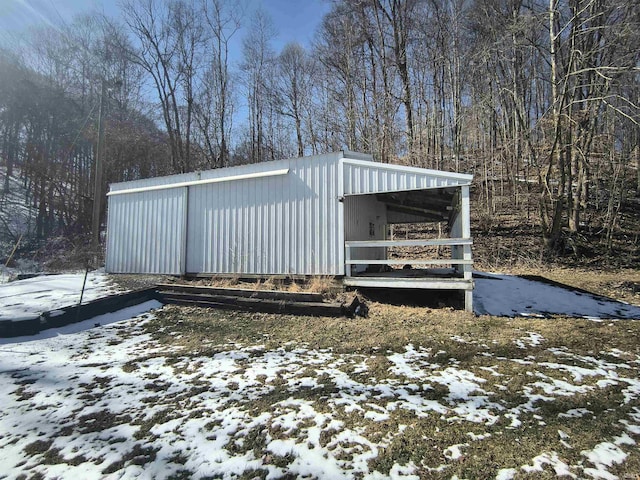 snow covered structure featuring an outbuilding and an outdoor structure