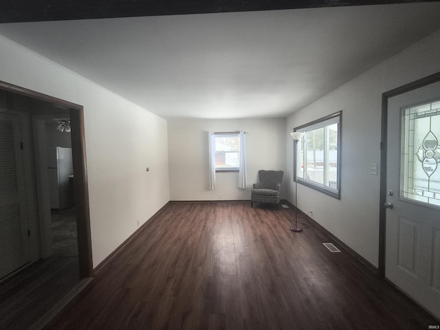 unfurnished room featuring baseboards, visible vents, and dark wood finished floors