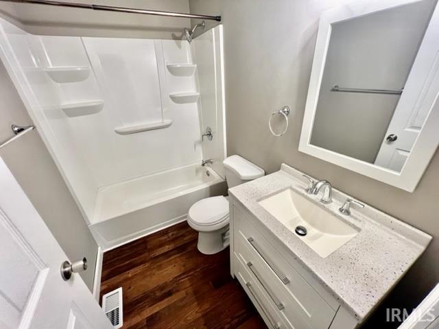 full bath featuring toilet, wood finished floors, vanity, visible vents, and shower / bathing tub combination