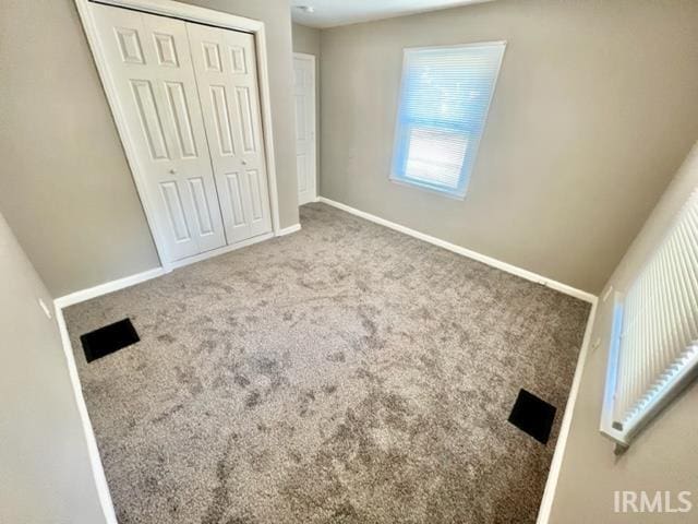 unfurnished bedroom featuring carpet floors, baseboards, and a closet