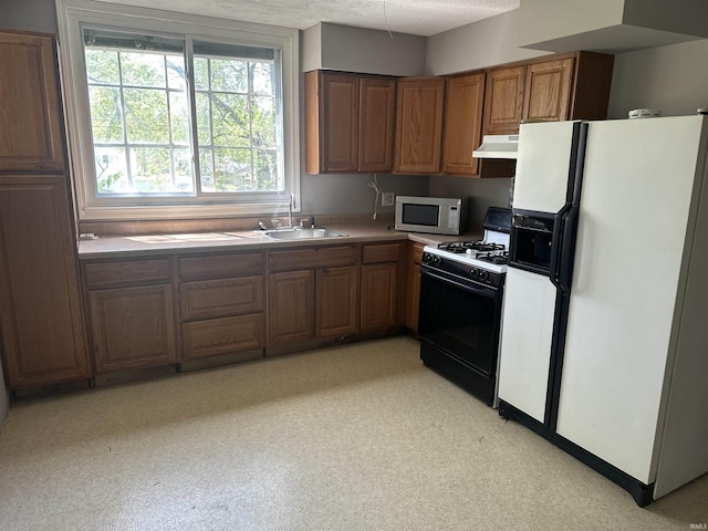 906 Varner Ave, Evansville, IN 47720 - kitchen with a sink, gas range oven, white refrigerator with ice dispenser, brown cabinetry, and under cabinet range hood