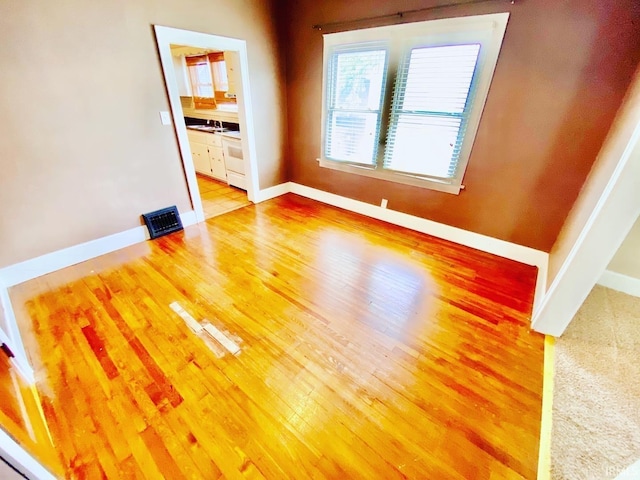 spare room featuring light wood finished floors, baseboards, and visible vents