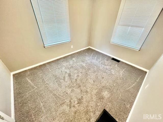 carpeted spare room with baseboards and visible vents