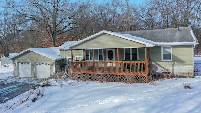 single story home featuring covered porch, a shingled roof, and a garage