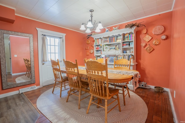 dining room featuring ornamental molding, visible vents, an inviting chandelier, and wood finished floors