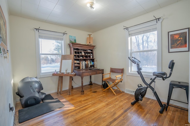 workout room featuring ornamental molding, baseboards, visible vents, and light wood finished floors