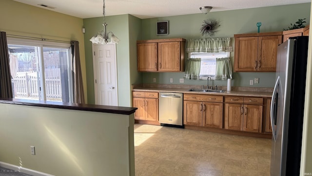 kitchen with appliances with stainless steel finishes, a sink, visible vents, and brown cabinets