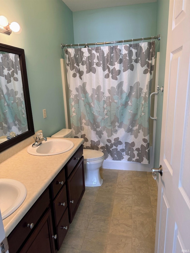 bathroom featuring double vanity, curtained shower, a sink, and toilet