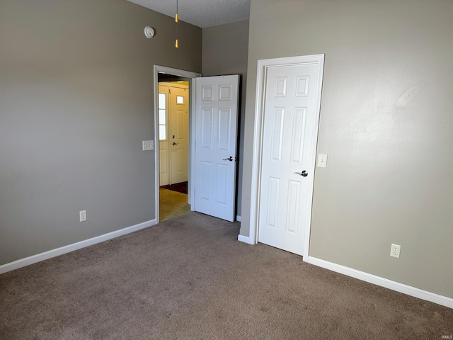 spare room with carpet floors, a textured ceiling, and baseboards