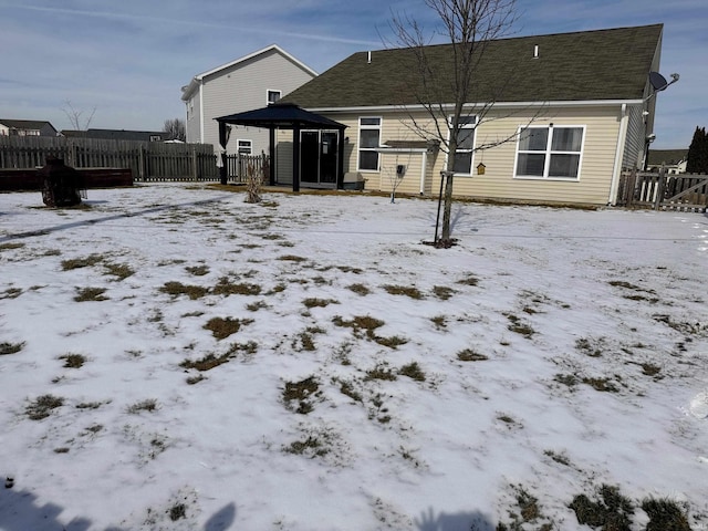 snow covered house featuring fence