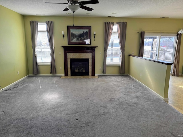 unfurnished living room featuring a wealth of natural light, carpet, and a tile fireplace