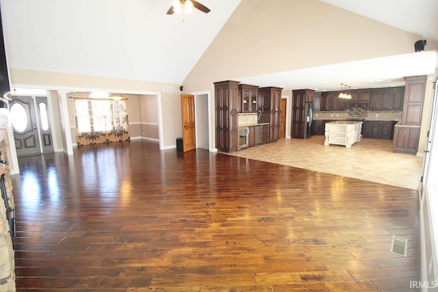 unfurnished living room with visible vents, high vaulted ceiling, wood finished floors, and ceiling fan with notable chandelier