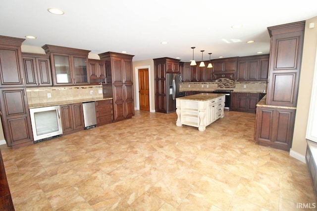 kitchen with glass insert cabinets, appliances with stainless steel finishes, light countertops, pendant lighting, and backsplash