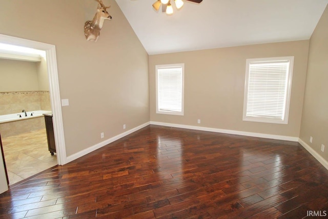 interior space featuring dark wood-style floors, ceiling fan, baseboards, and vaulted ceiling