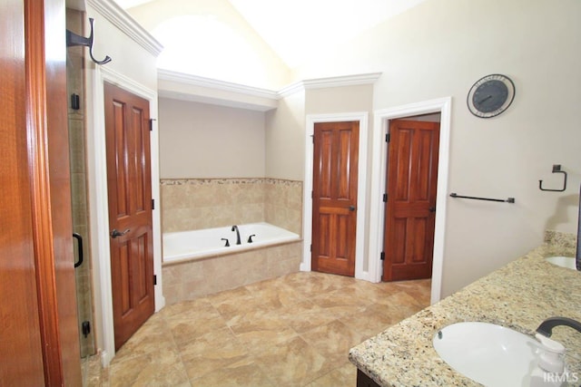 bathroom with a garden tub, double vanity, lofted ceiling, a stall shower, and a sink