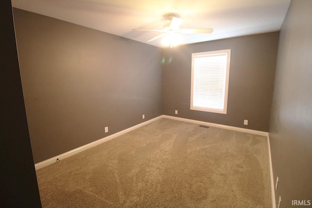 carpeted empty room with a ceiling fan and baseboards