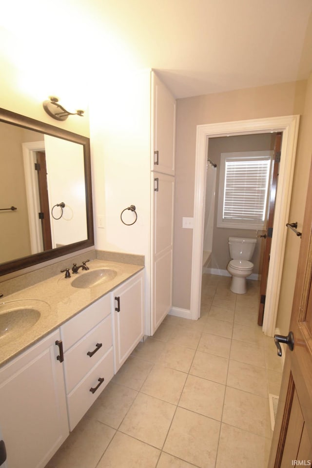 full bath featuring double vanity, a sink, toilet, and tile patterned floors