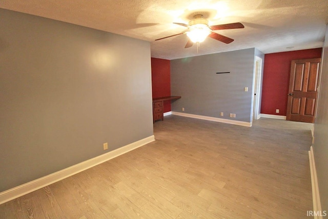 unfurnished room featuring light wood-style floors, ceiling fan, baseboards, and a textured ceiling