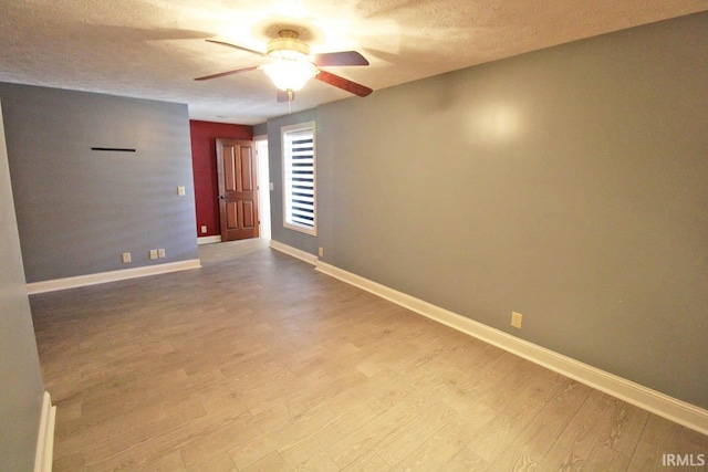 unfurnished room with a textured ceiling, light wood finished floors, a ceiling fan, and baseboards