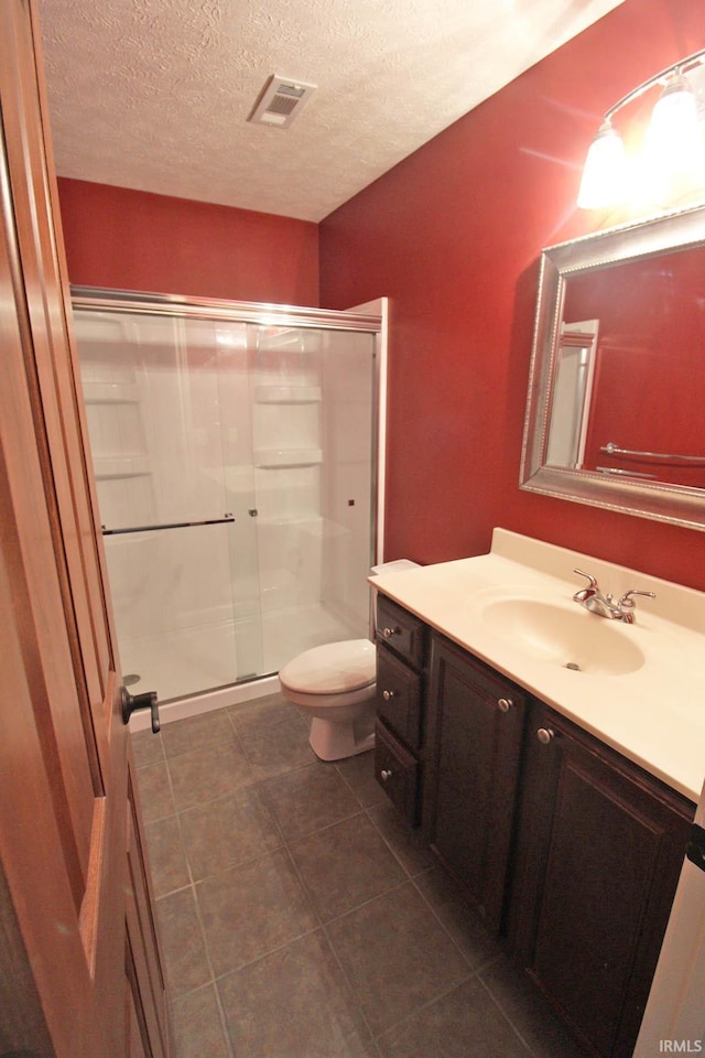 full bath with visible vents, toilet, a shower stall, vanity, and a textured ceiling