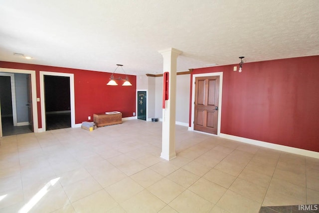 interior space with ornate columns, baseboards, a textured ceiling, and light tile patterned flooring